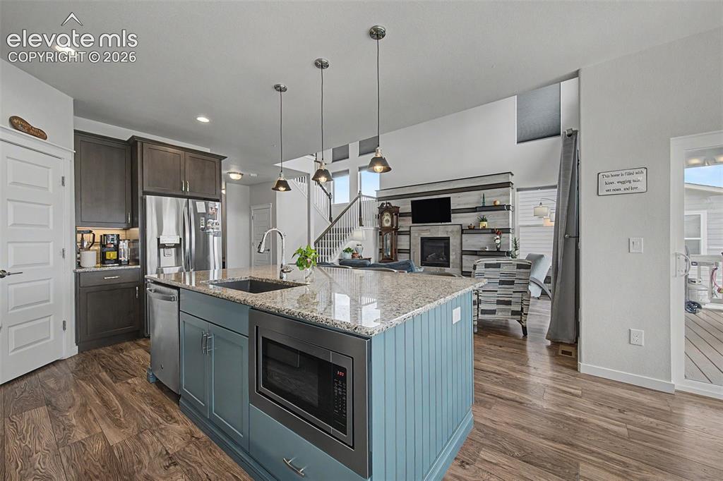 Image 13 of 45: The island features a farmhouse sink, built-in microwave and dishwasher.