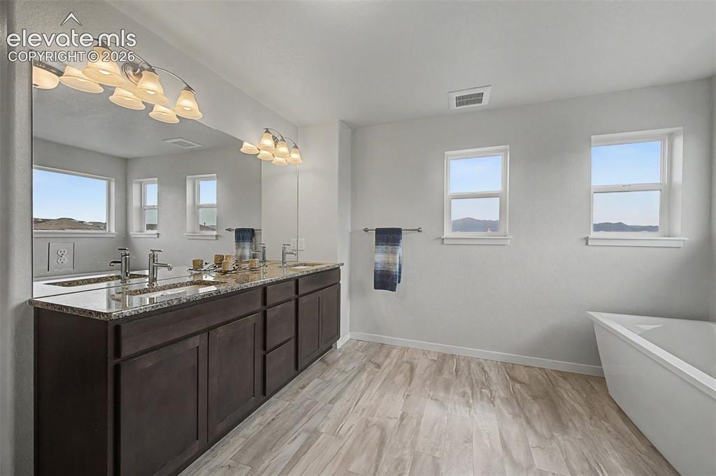 Image 27 of 45: A granite topped double vanity provides so much storage in the primary bath