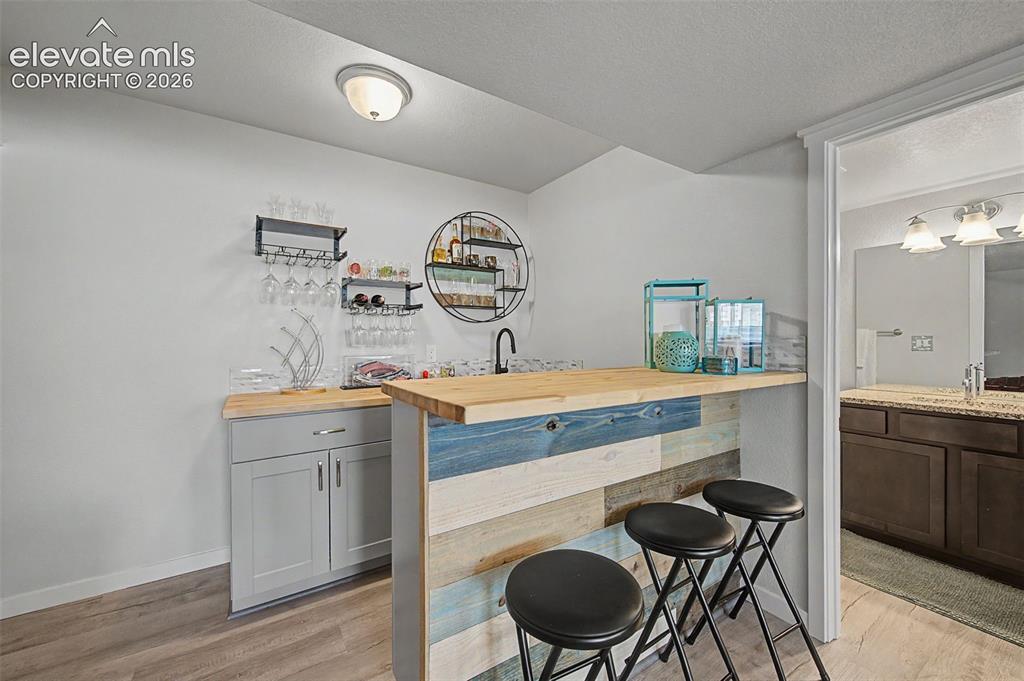 Image 36 of 45: Wet bar in basement family room comes equipped with a wine fridge.