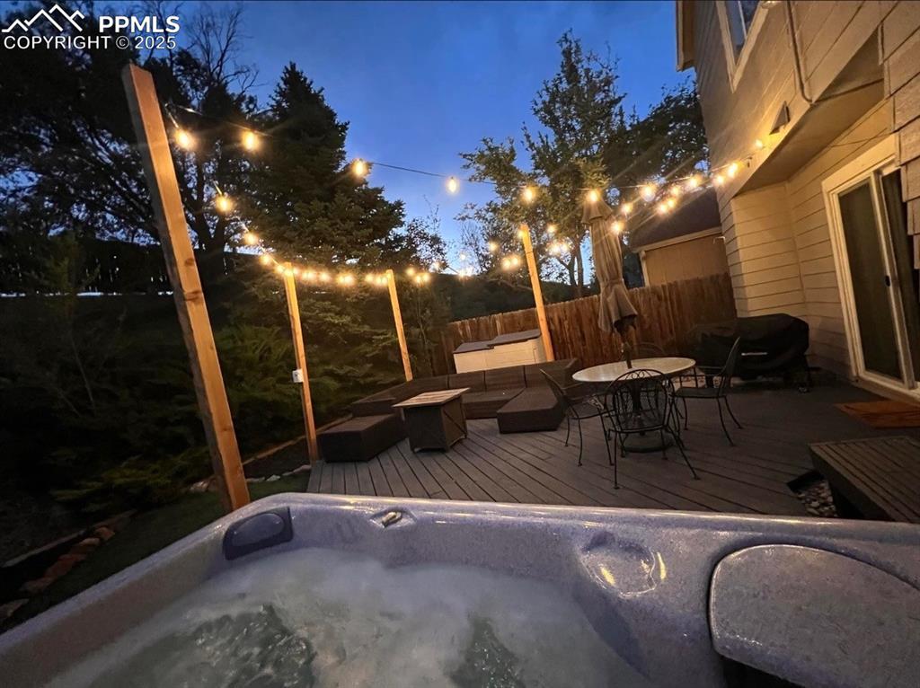 Image 32 of 41: Wooden deck with an outdoor hot tub and outdoor dining area