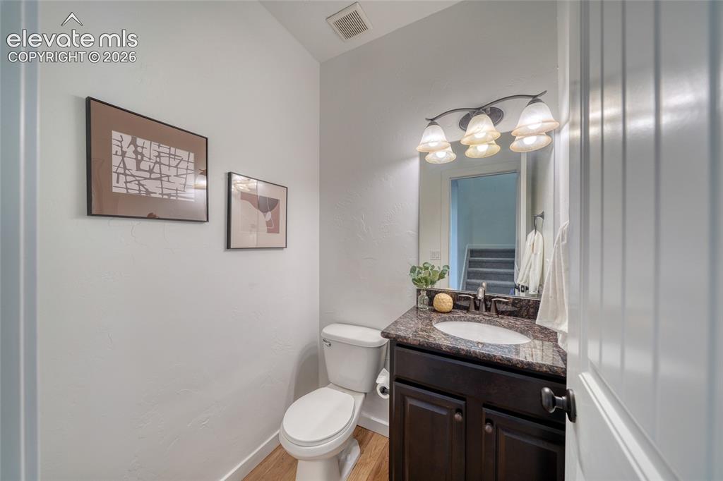 Image 13 of 49: Powder room featuring a dark wood-finish vanity, stone-look countertop, int