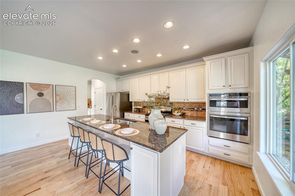 Image 15 of 49: Kitchen featuring a large island with sink, ample white cabinetry, stainles