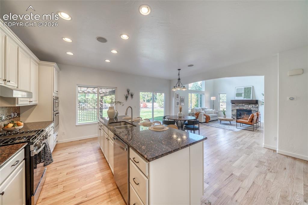 Image 17 of 49: Open-concept kitchen with light wood-finish flooring, recessed lighting, an