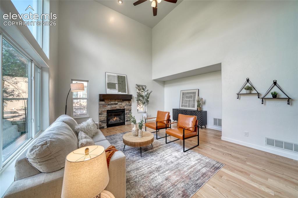 Image 19 of 49: Soaring ceilings with recessed lighting, a stone-faced fireplace with a woo