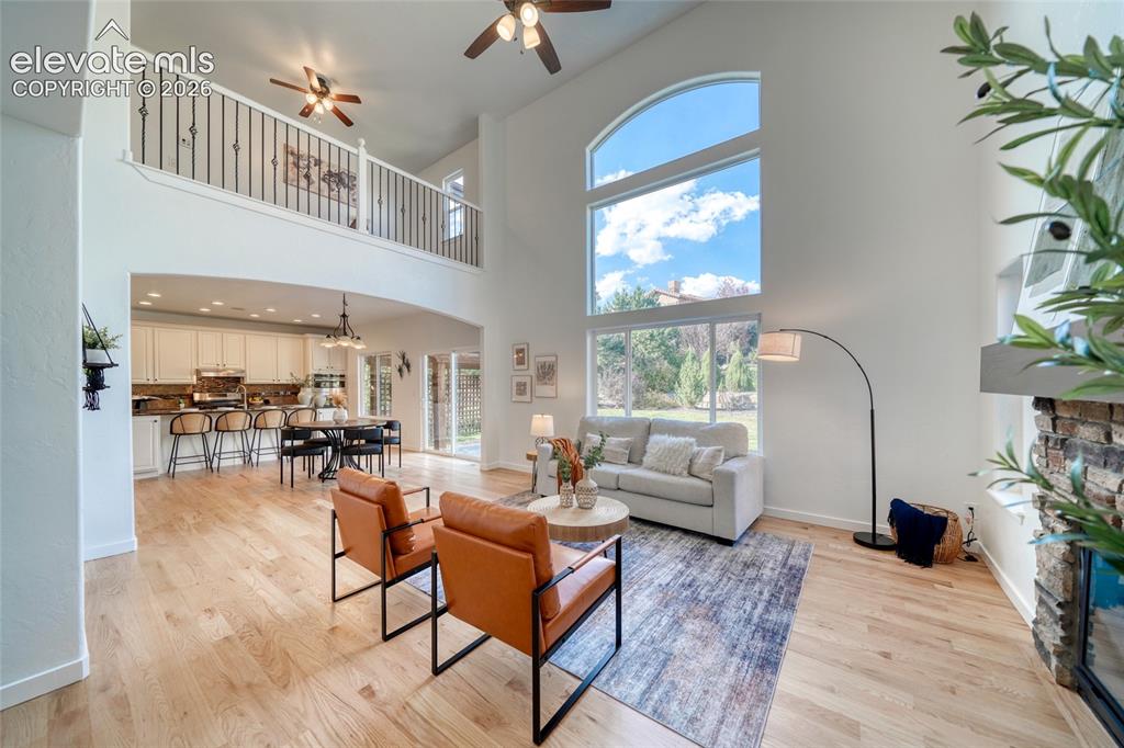 Image 20 of 49: Two-story living area with hardwood flooring, a fireplace with stone surrou