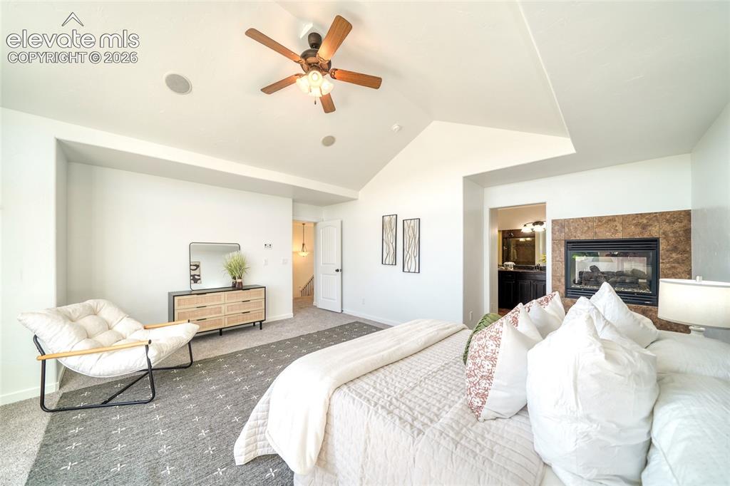 Image 25 of 49: Vaulted ceiling with a ceiling fan, built-in fireplace with stone-finish su