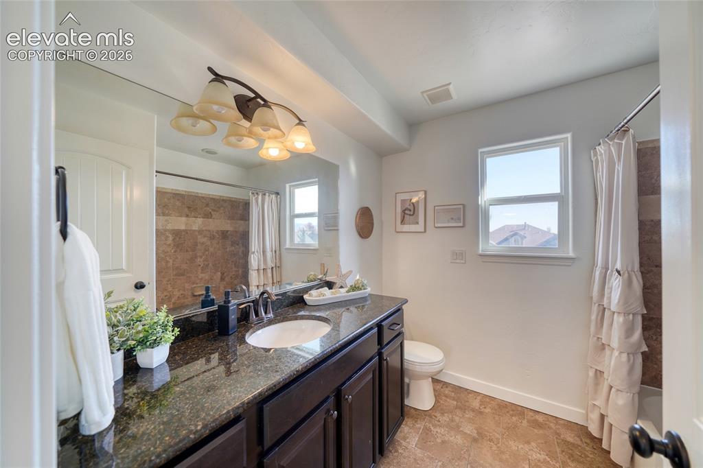 Image 32 of 49: Vanity with a dark countertop and undermount sink, dark wood-finish cabinet