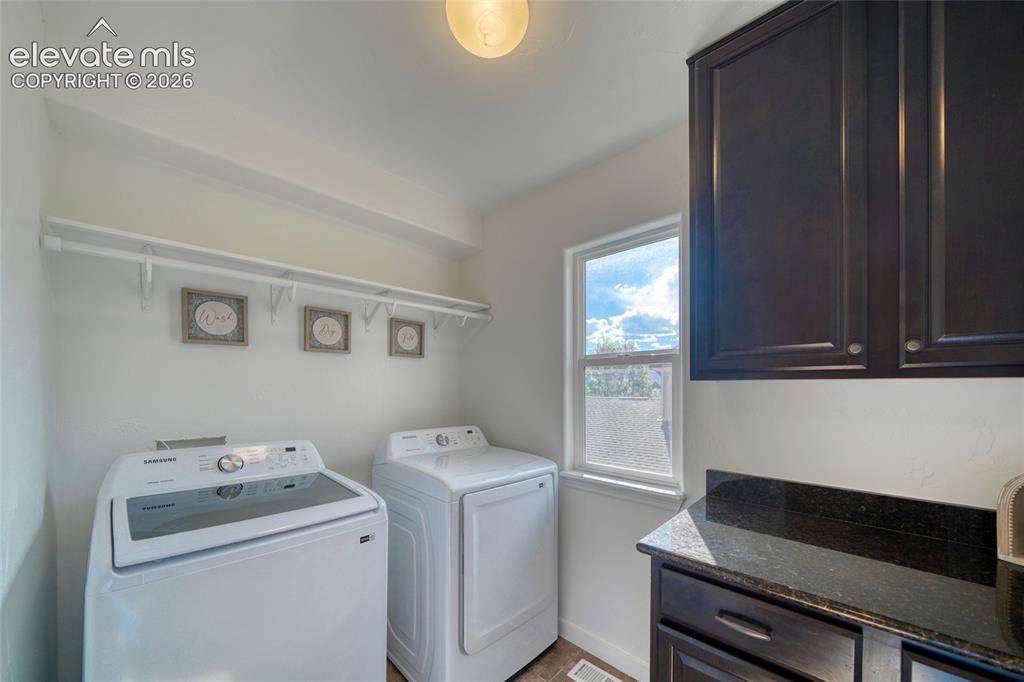 Image 33 of 49: Laundry room with built-in shelving, dark wood-finish cabinetry, and a wind