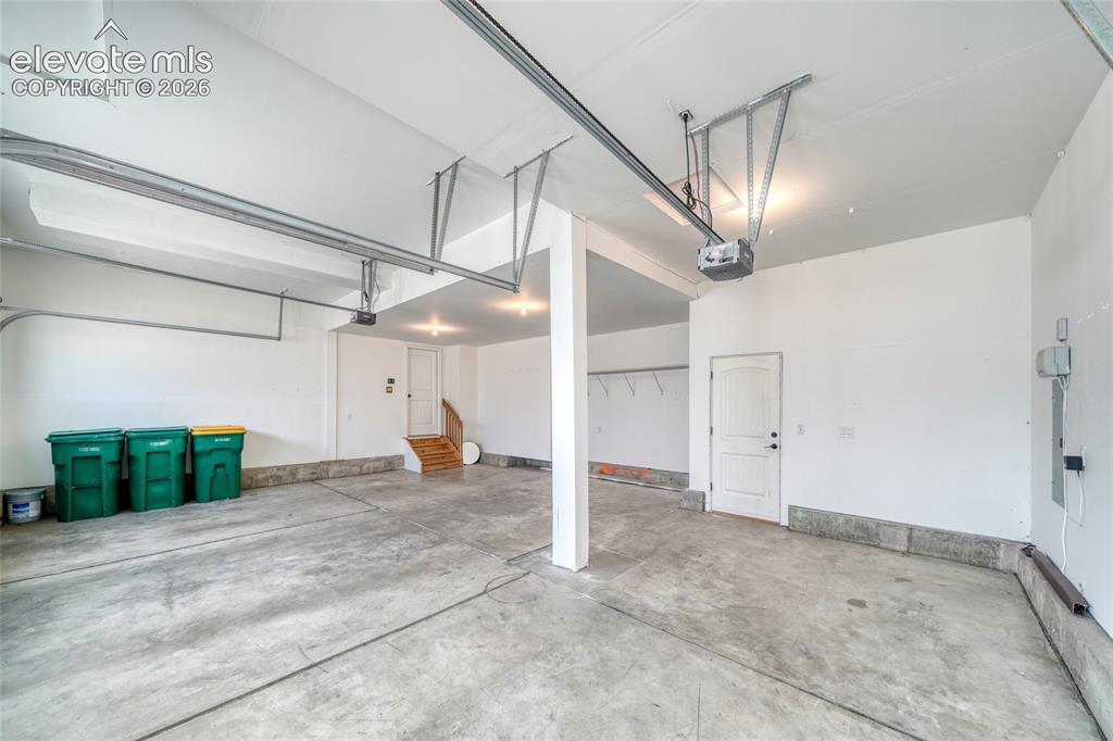 Image 37 of 49: Spacious garage with concrete flooring, automatic garage door opener, overh