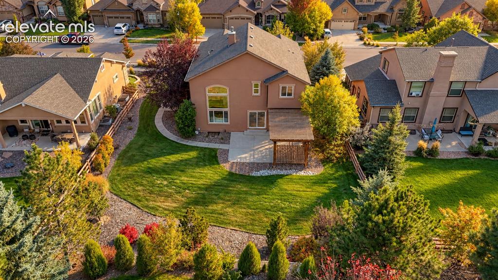 Image 4 of 49: Expansive green lawn with mature trees and shrubs, stucco exterior, rear pa