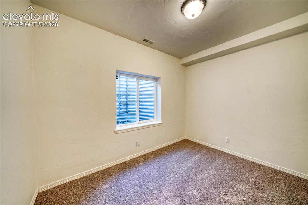 Image 41 of 49: Carpeted room with a single window and overhead flush-mount lighting