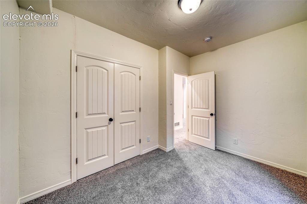 Image 42 of 49: Interior room with neutral wall color and grey carpet flooring