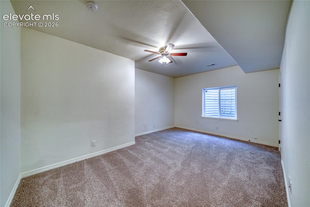 Image 43 of 49: Wall-to-wall carpeting, window with blinds, ceiling fan with integrated lig