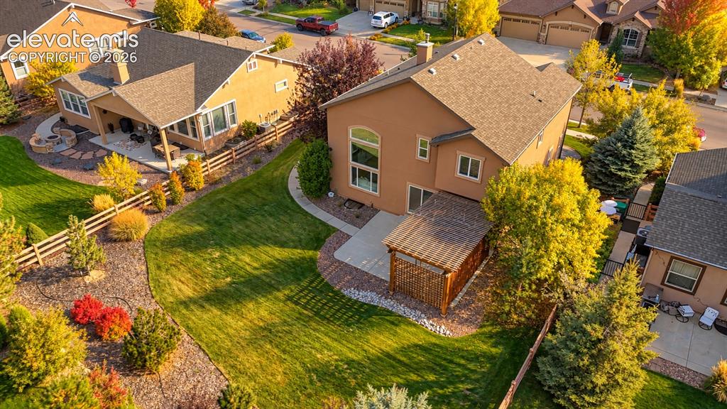 Image 5 of 49: Expansive lawn with mature trees, a covered patio, and a stone patio featur
