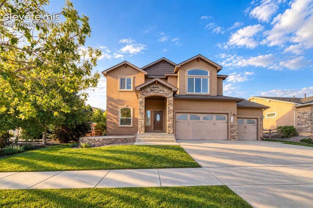 Image 7 of 49: Stucco exterior with stone accents, arched entry, multiple garages, arched 