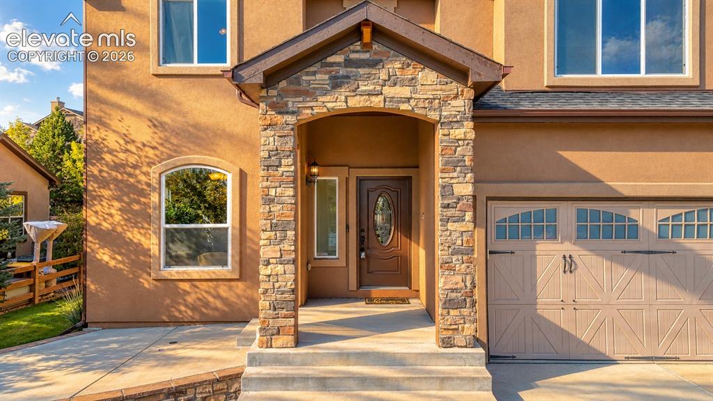 Image 8 of 49: Stucco exterior with stone accents, covered entry, arched front door with o
