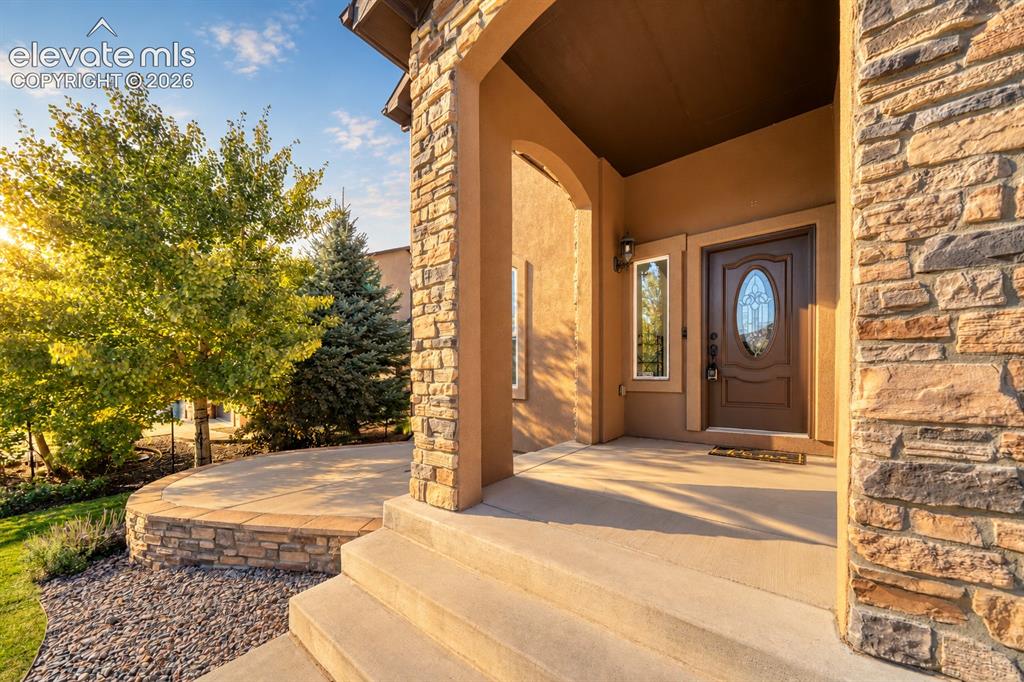 Image 9 of 49: Stone and stucco exterior detailing, covered entry, solid wood-finish entry