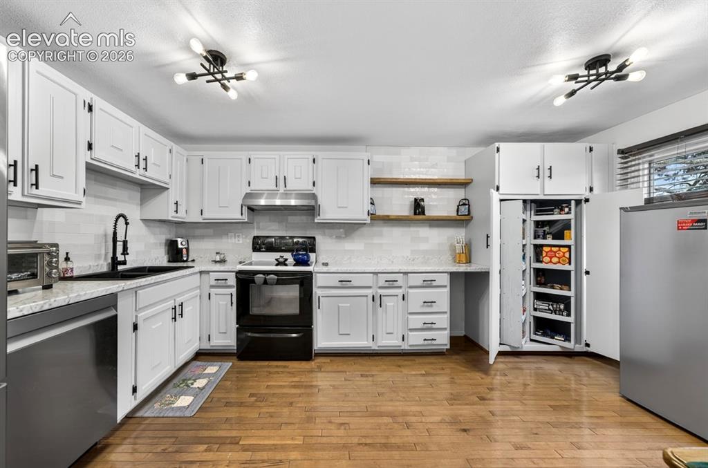 Image 10 of 42: Bright kitchen featuring white cabinetry with black hardware, a subway tile