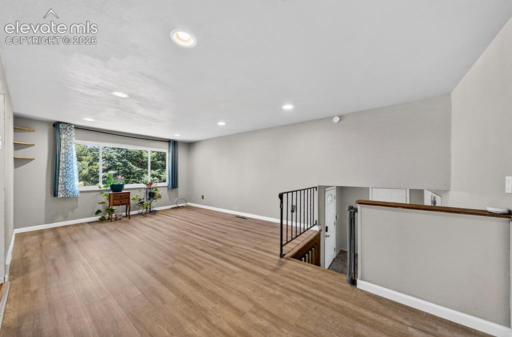 Image 11 of 42: Spacious room featuring wood-finish flooring, recessed lighting, and a larg