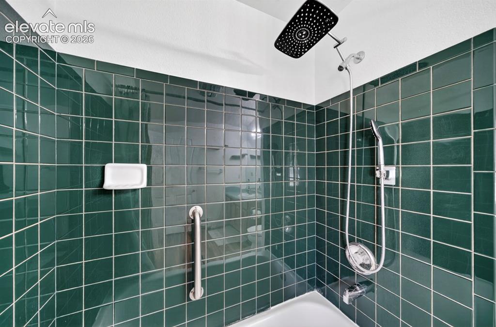 Image 17 of 42: Main Floor- Shower enclosure featuring dark green tile, a built-in soap dis