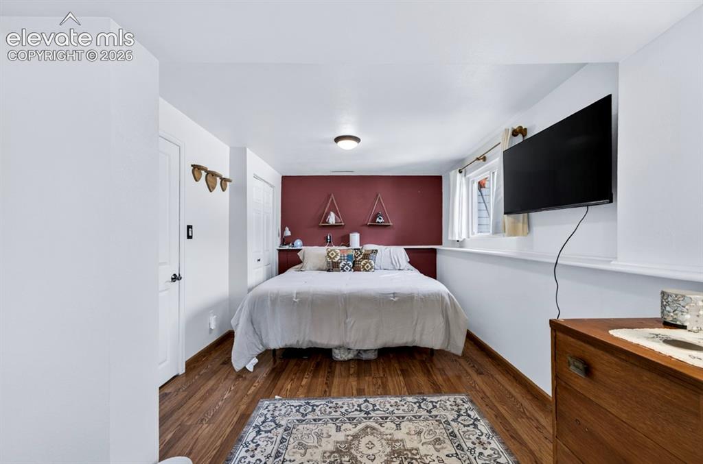 Image 18 of 42: Basement- Bedroom with wood-finish flooring, a feature wall, and a window