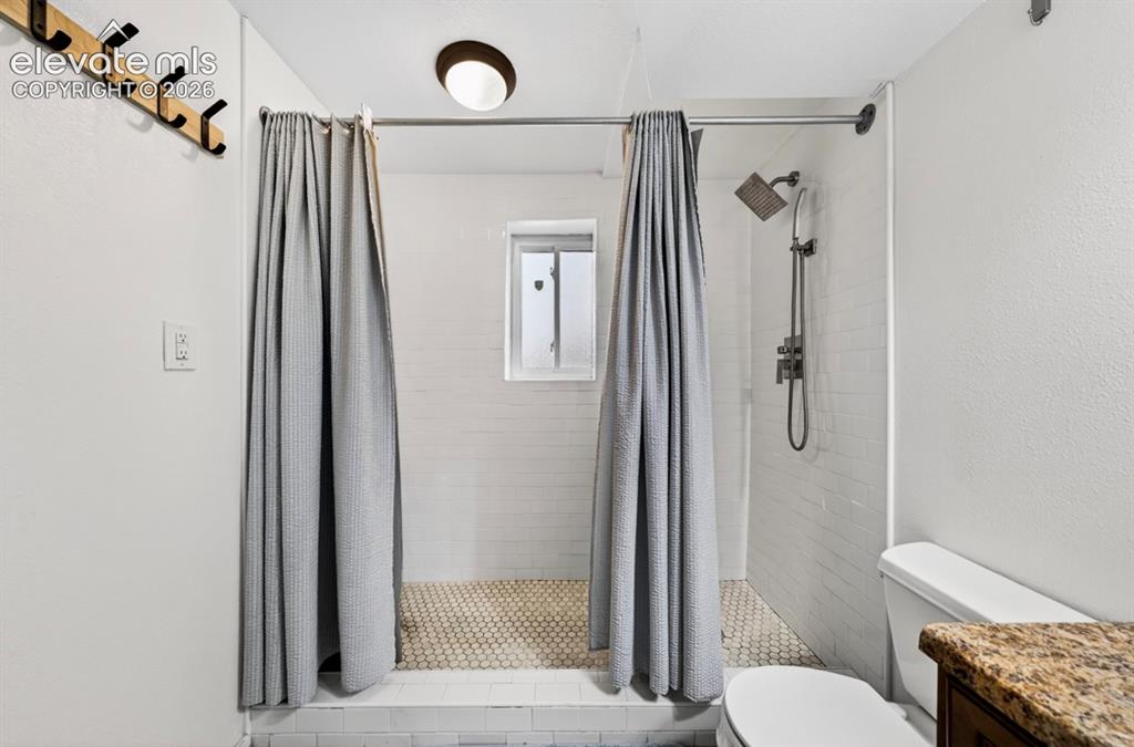 Image 22 of 42: Shower area featuring subway tile walls, a hexagonal mosaic tile floor, and