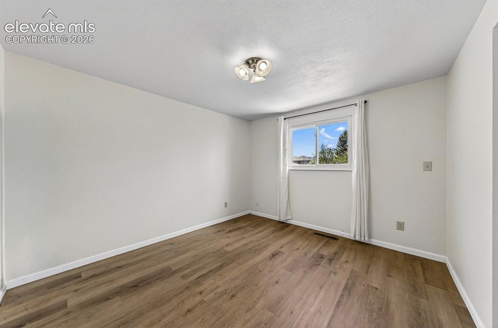 Image 29 of 42: Upper Level- Spacious room featuring wood-finish flooring, light-colored wa