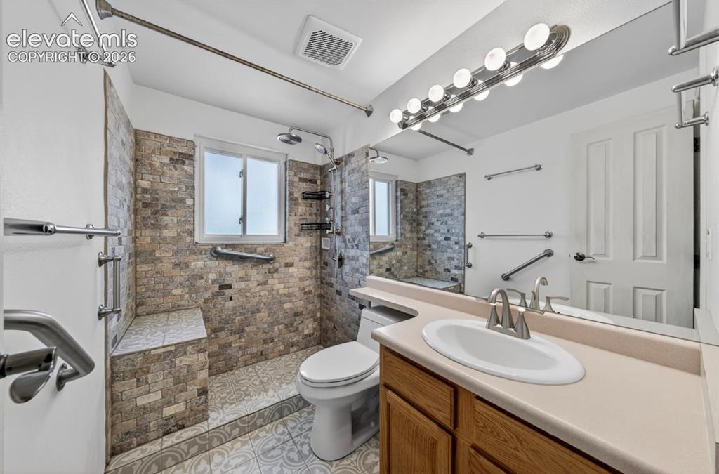 Image 30 of 42: Upper Level- Tiled shower featuring a built-in bench, two showerheads, and