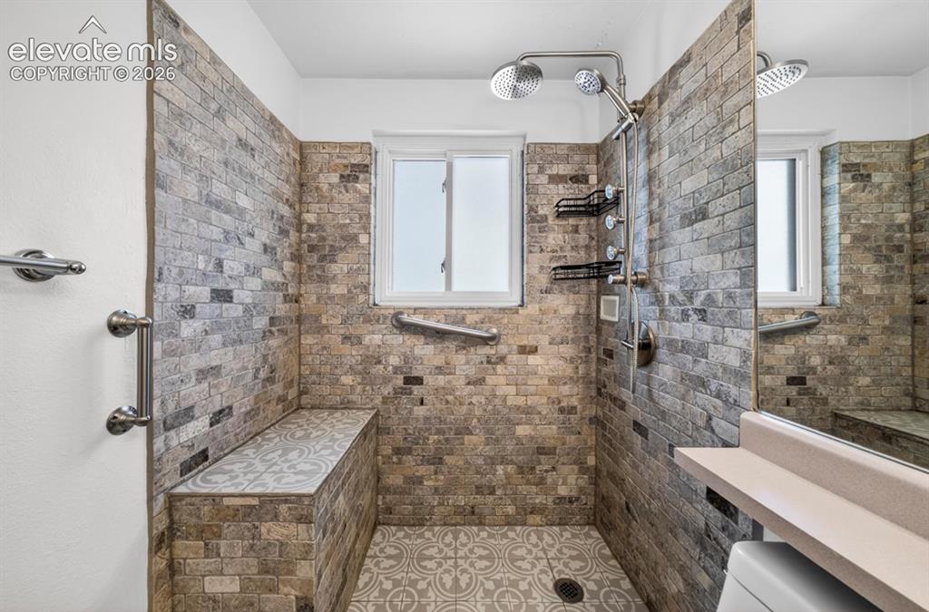 Image 31 of 42: Upper Level- Spacious shower with stone-finish tile walls and patterned til