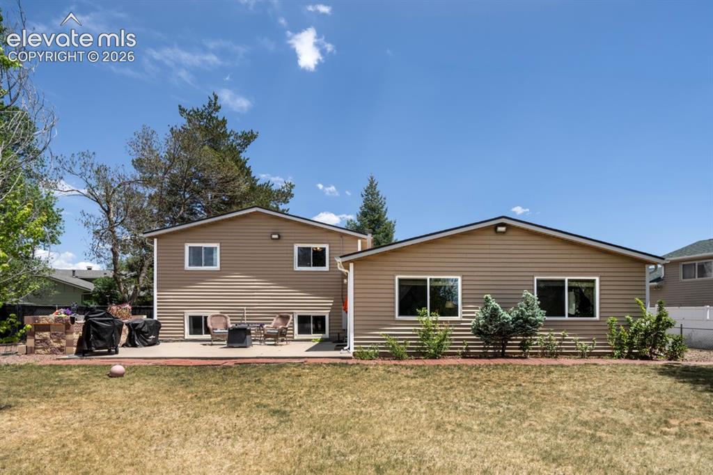 Image 32 of 42: Expansive backyard with a large lawn, mature trees, and a spacious concrete