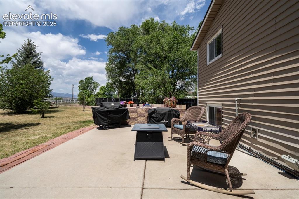 Image 33 of 42: Concrete patio featuring a low stone wall, a built-in countertop, and a win