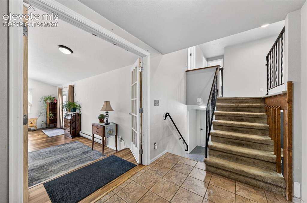 Image 8 of 42: Foyer featuring tile flooring, staircase with carpeted treads and wrought i