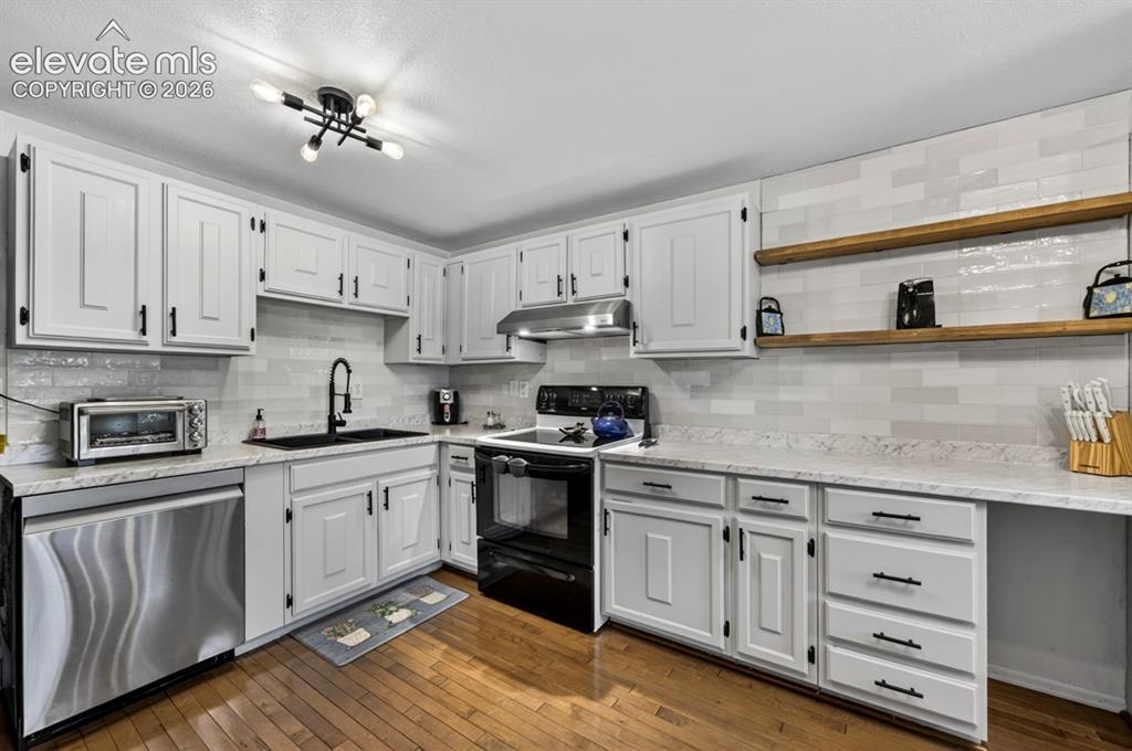 Image 9 of 42: Kitchen featuring white shaker-style cabinetry with black hardware, white s