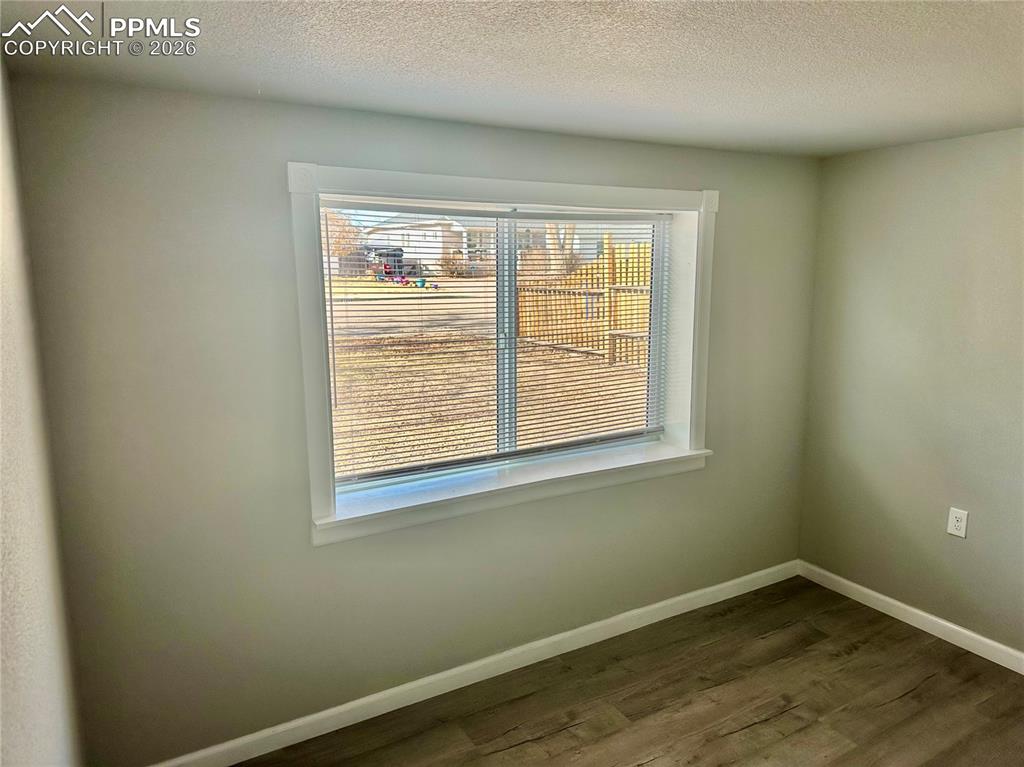 Image 10 of 21: Unfurnished room featuring dark wood-style flooring and a textured ceiling