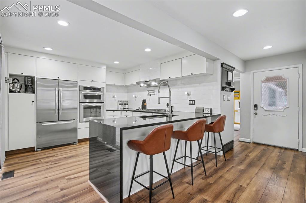 Image 5 of 36: Updated Kitchen with sleek flat-front cabinetry, waterfall-edge slab granit
