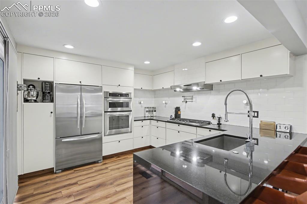 Image 6 of 36: Updated Kitchen with sleek flat-front cabinetry, waterfall-edge slab granit