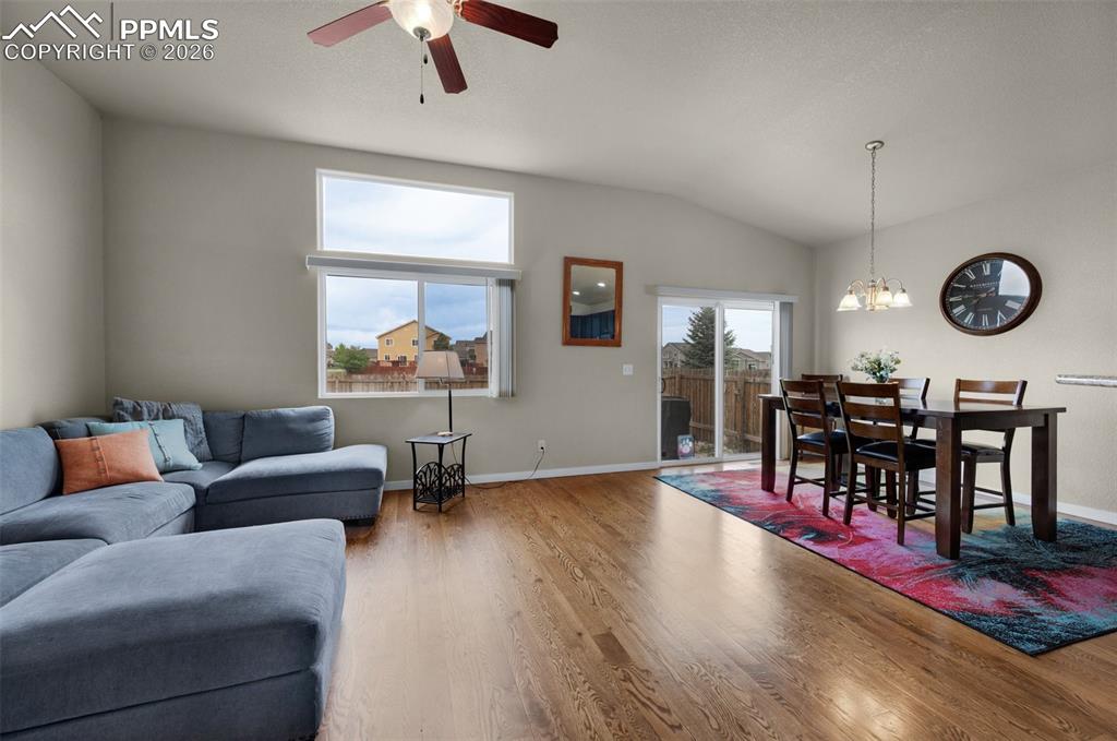 Image 6 of 31: Living room with oak hardwood flooring, ceiling fan, and vaulted ceiling,