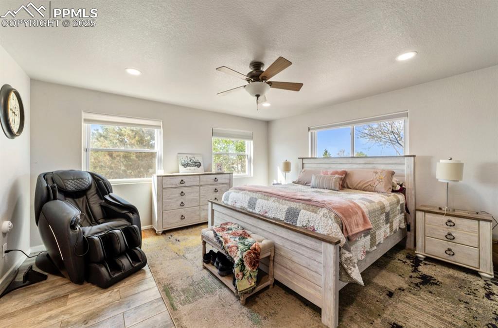 Image 10 of 21: Bedroom with light wood-style floors, recessed lighting, and a textured cei