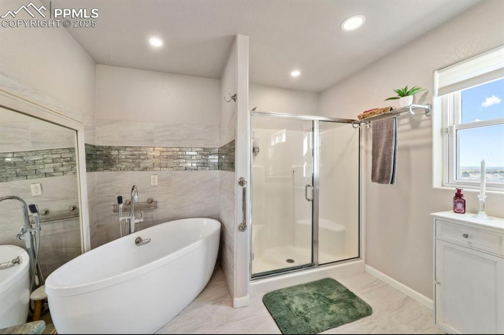 Image 12 of 21: Bathroom with vanity, baseboards, recessed lighting, a soaking tub, and a s