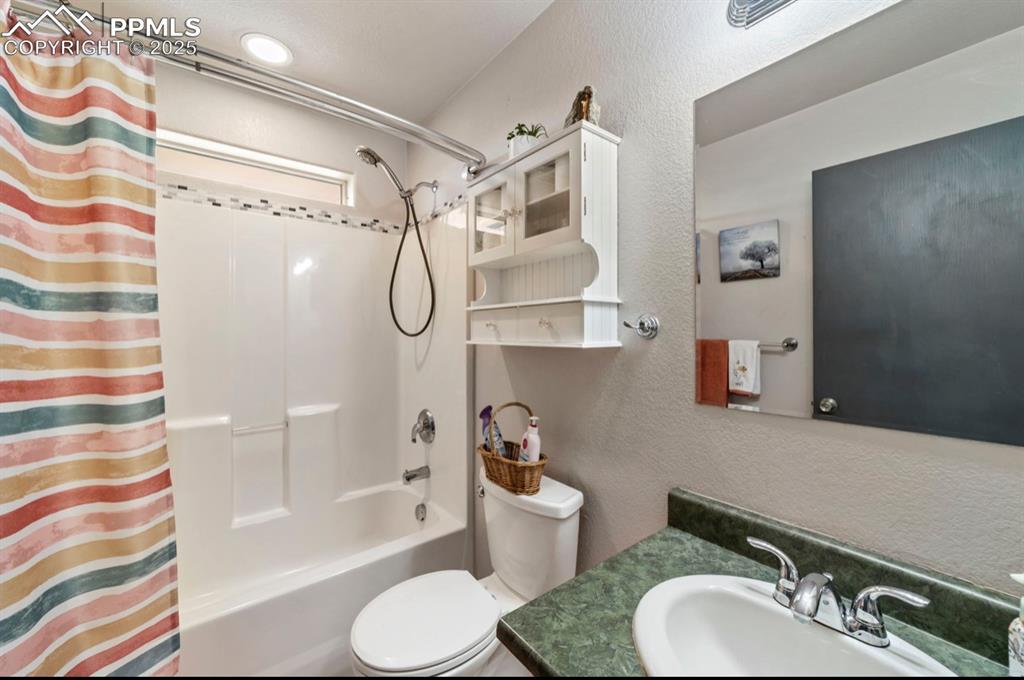 Image 15 of 21: Bathroom with vanity, toilet, a textured wall, and shower / bath combo with