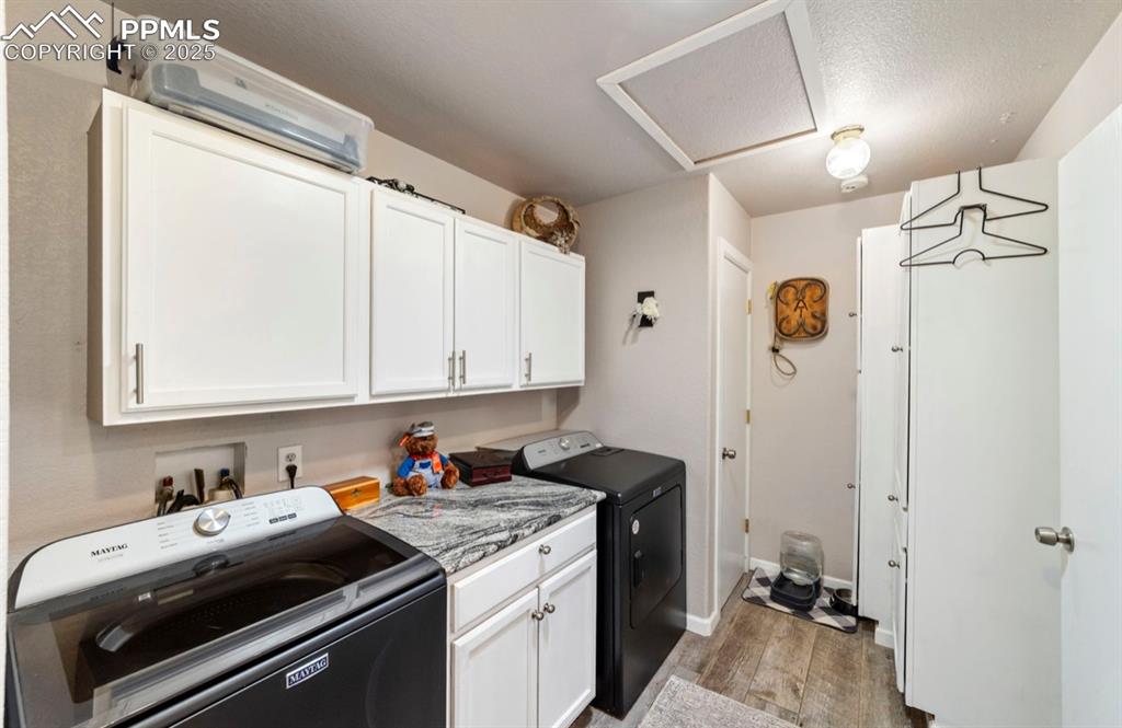Image 16 of 21: Laundry area featuring washer and dryer, cabinet space, light wood-style fl