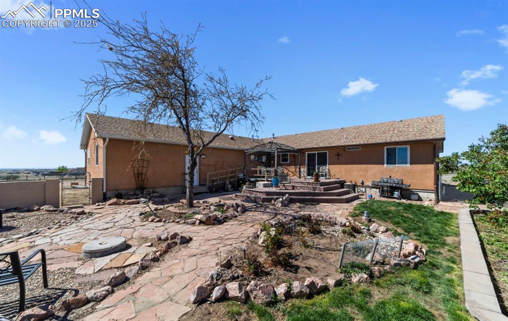 Image 20 of 21: Rear view of property featuring fence, a gate, a patio, and stucco siding