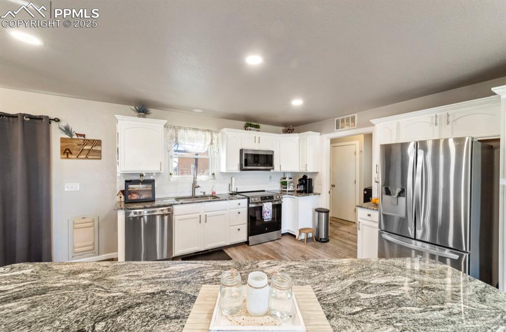 Image 6 of 21: Kitchen with a sink, dark stone countertops, appliances with stainless stee