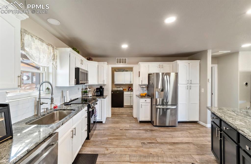 Image 7 of 21: Kitchen featuring white cabinets, a sink, light wood-style flooring, washer
