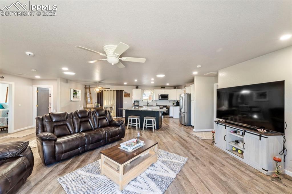 Image 8 of 21: Living area featuring light wood-type flooring, recessed lighting, baseboar