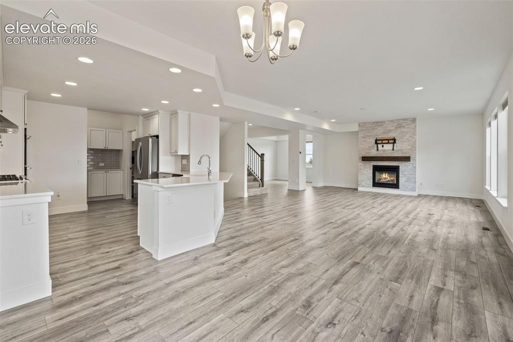 Image 12 of 50: Expansive open-concept living area featuring wood-finish LVP flooring, a co