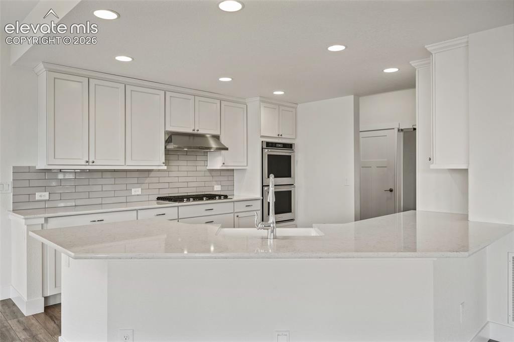 Image 13 of 50: White shaker cabinetry, light-toned countertops, subway tile backsplash, st