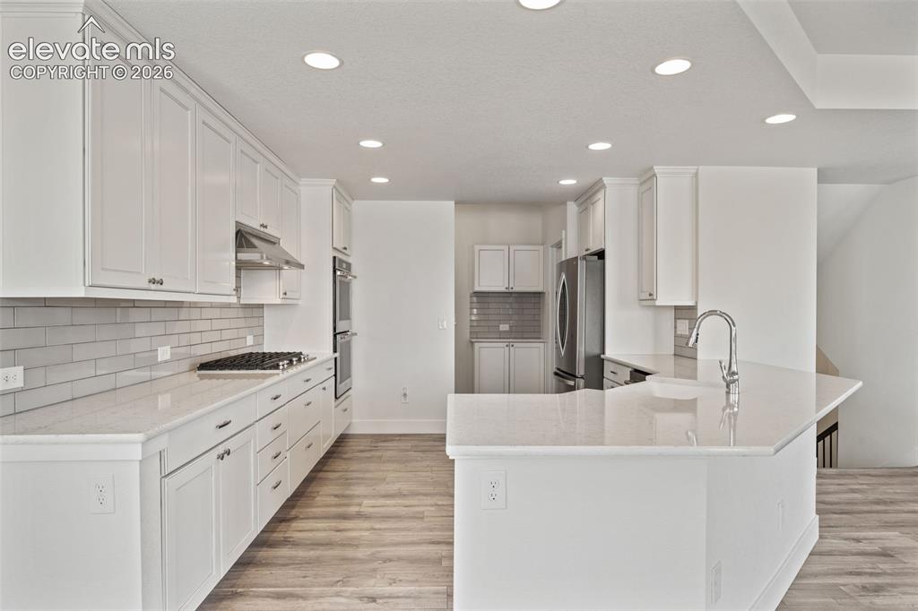 Image 14 of 50: White shaker cabinetry, light-toned countertops, subway tile backsplash, st