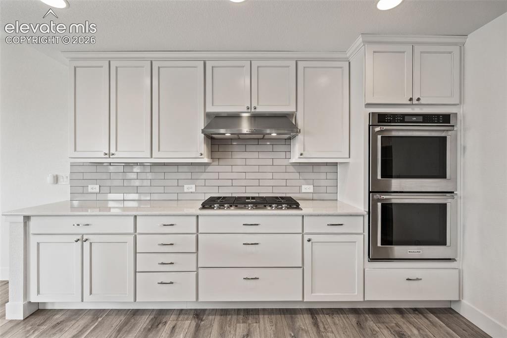 Image 15 of 50: White shaker cabinetry, light subway tile backsplash, stainless steel gas c