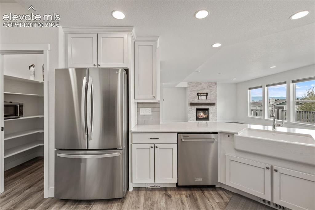 Image 16 of 50: White shaker cabinetry, stainless steel appliances, wood-finish LVP floorin